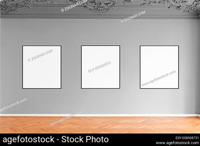 three empty picture frames hanging on grey wall in gallery