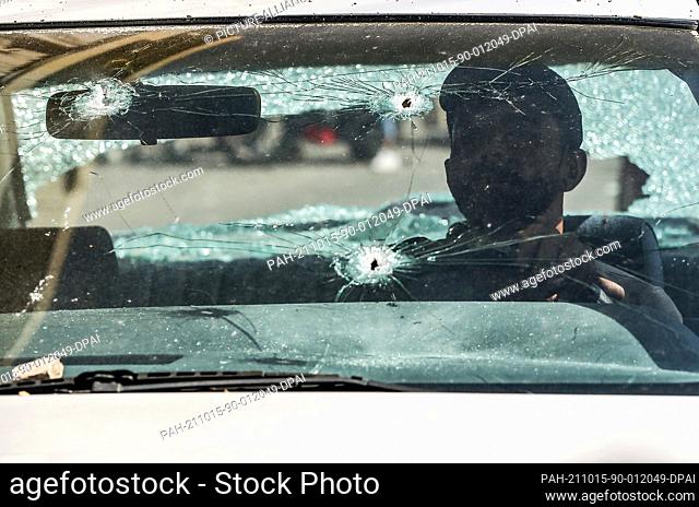 15 October 2021, Lebanon, Beirut: A man sits inside his bullet riddled car in the Tayouneh, following yesterday's deadly violent clashes between Muslim Shiite...