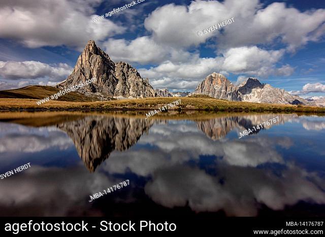 Ra Gusela and other mountains in the Dolomites are reflected in a puddle at Passo Giau