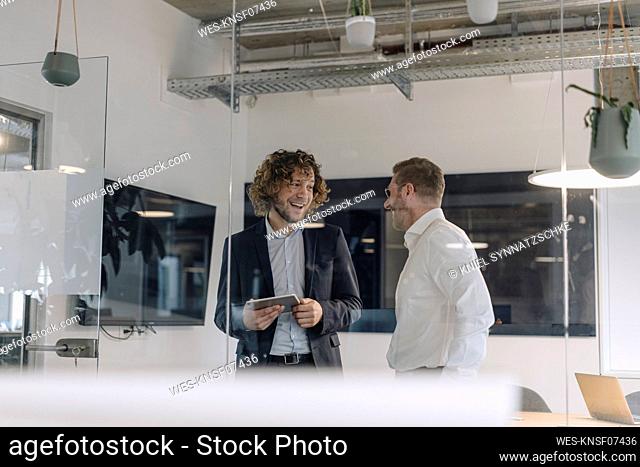 Two happy businessmen talking in office