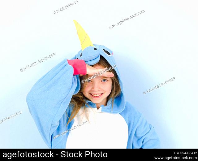 pretty blonde girl with cozy blue unicorn costume is posing in the studio in front of blue wall