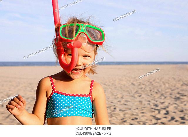 Girl on beach wearing snorkel looking at camera smiling