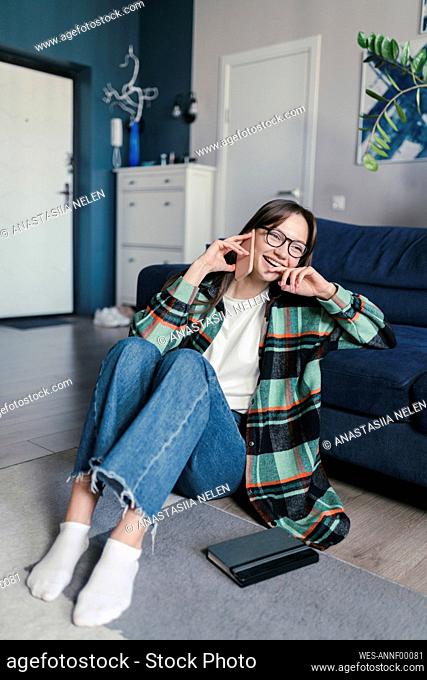 Happy woman wearing eyeglasses talking on smart phone sitting at home