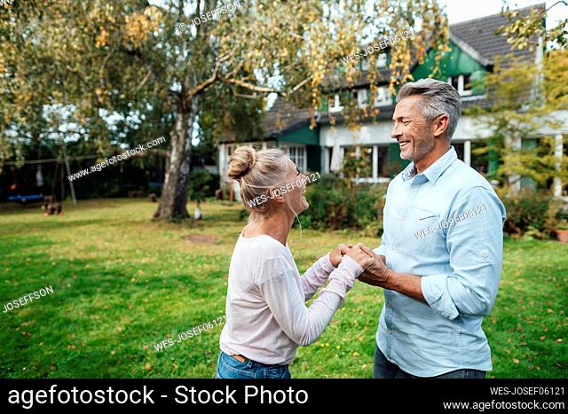 Smiling couple holding each other hands at backyard