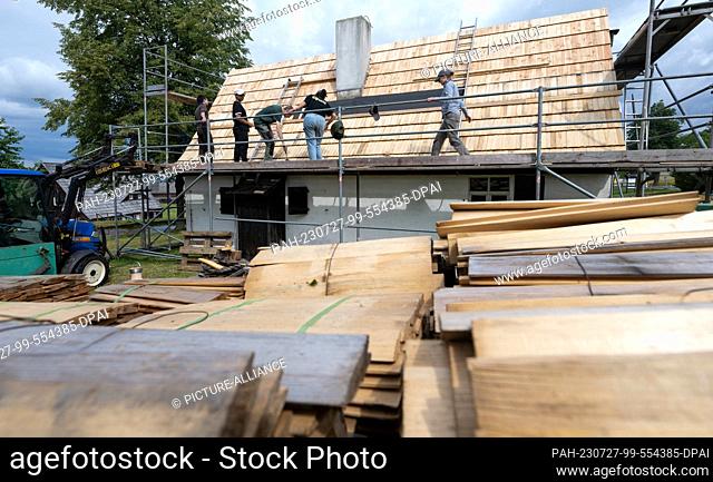 27 July 2023, Saxony, Seiffen: Young people from different countries are restoring the shingle roof of the rafters' dwelling in the Seiffen Open-Air Museum