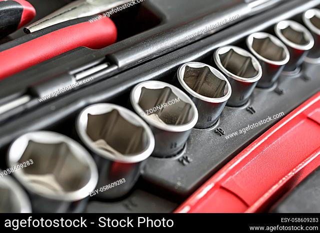 Chrome nozzles and red-black pliers in the dark toolbox. Low aperture closeup photo. Horizontal