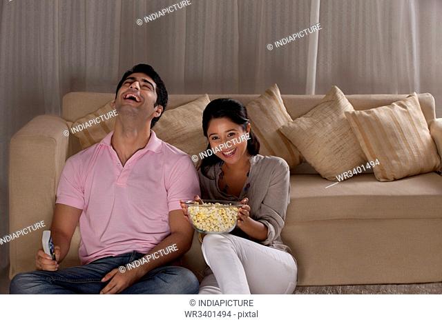 Cheerful young couple enjoying the movie at home