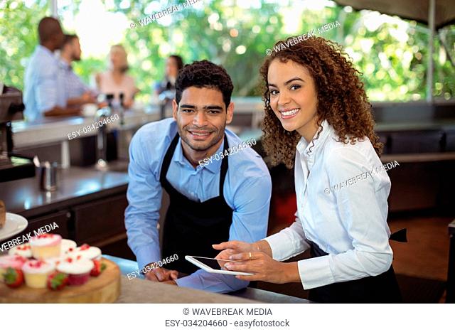 Male waiter and female waitress with digital tablet