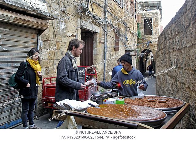 01 February 2019, Lebanon, Sidon: A foreigner buys sweets from a street vendor in the old quarter of the Lebanese port city of Sidon
