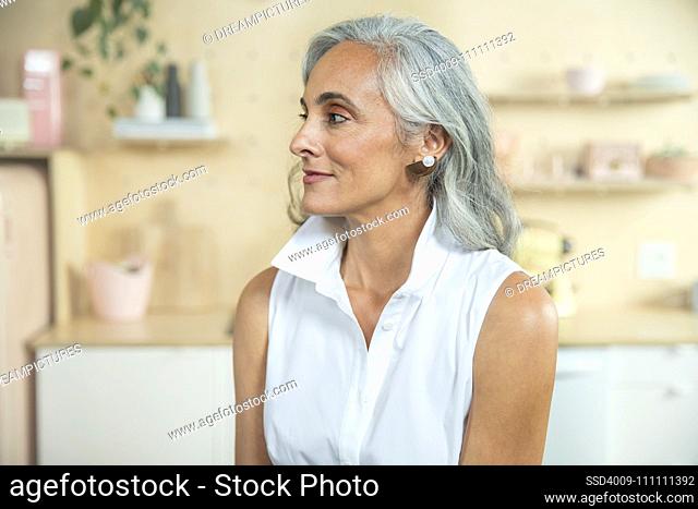 Horizontal close up portrait of middle-aged woman looking off camera in her kitchen