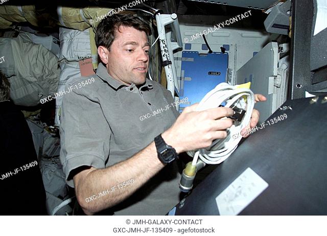 Astronaut Jeffrey S. Ashby, pilot, unpacks some cable on the mid deck of the Space Shuttle Endeavour as the seven-member STS-100 crew busily prepares for its...