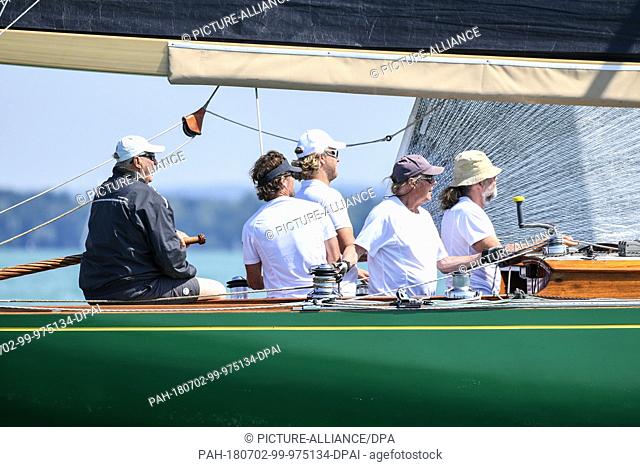 02 July 2018, Germany, Langenargen: King Harald V. of Norway (L) sitting at the tiller on his yacht 'Sira' during the sailing world championship 8 metre...