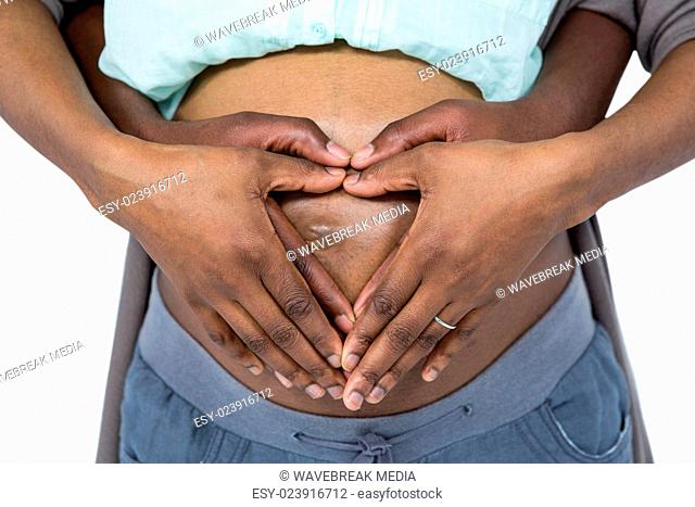 Couple making a heart shape on belly