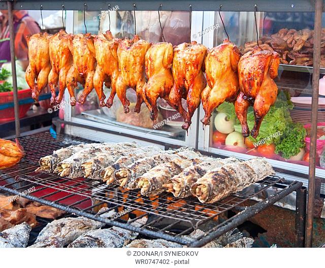 Row of grilled fish and hens on the street market