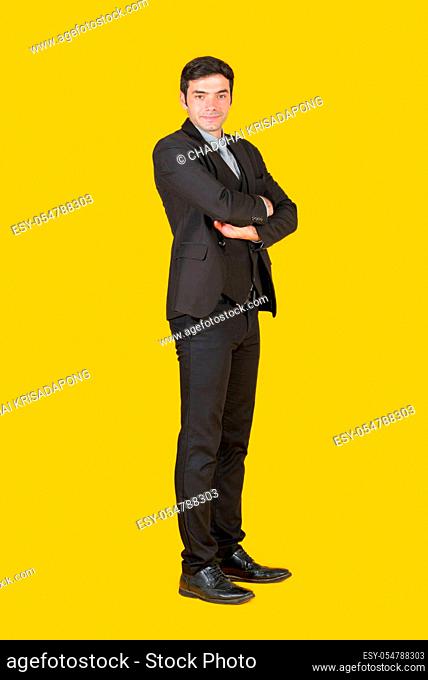 A young businessman in a gray shirt and a black suit fold his arms over the chest with confidence. The concept of investing in a successful business