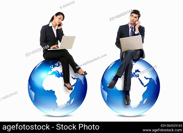 Male and female corporate Co-workers working on laptop and talking on phone sittting on distant graphic earth