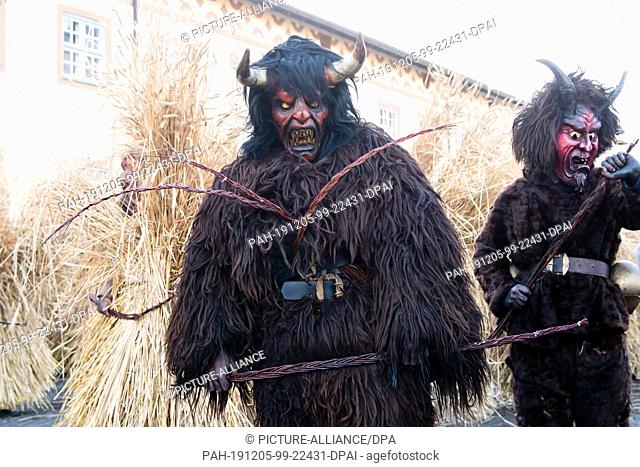 05 December 2019, Bavaria, Berchtesgaden: Kramperl and Buttmandl are walking through the village during the traditional Buttnmandll race of the German Armed...