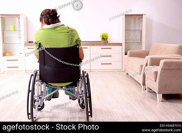 The young male invalid in wheel-chair suffering at home