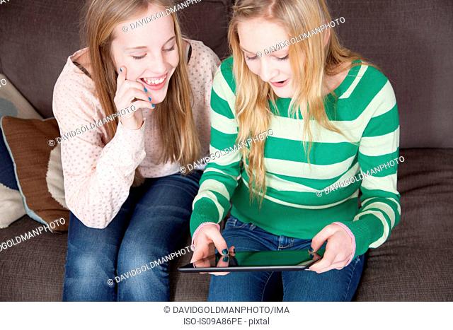 Girls sitting on sofa looking at digital tablet