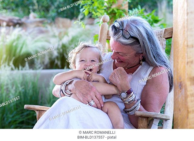Caucasian older woman holding grandson in rocking chair