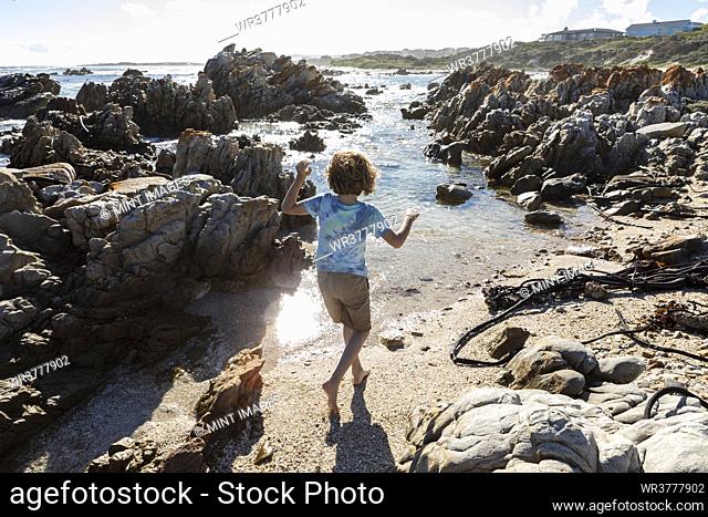 Eight year old boy exploring a rocky beach