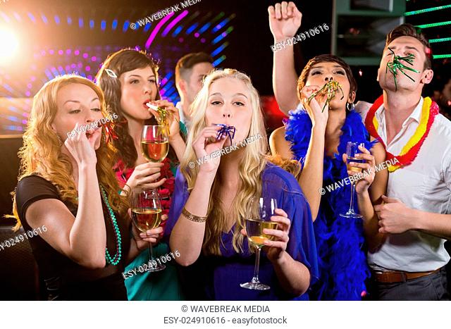 Group of friends blowing party horn in bar