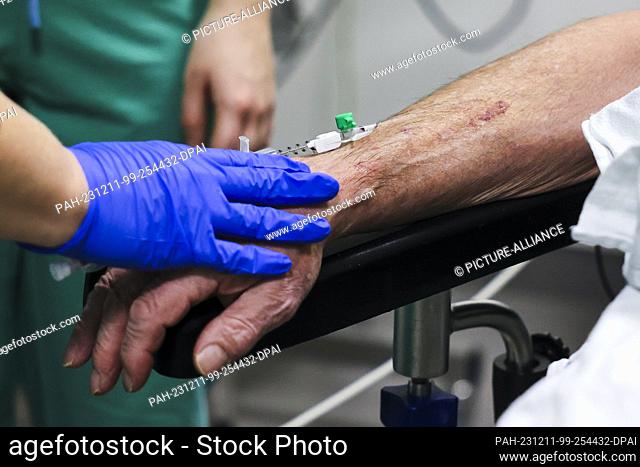 PRODUCTION - 29 November 2023, Schleswig-Holstein, Rendsburg: An anesthesia nurse performs an intravenous induction of anesthesia on a patient in the surgical...