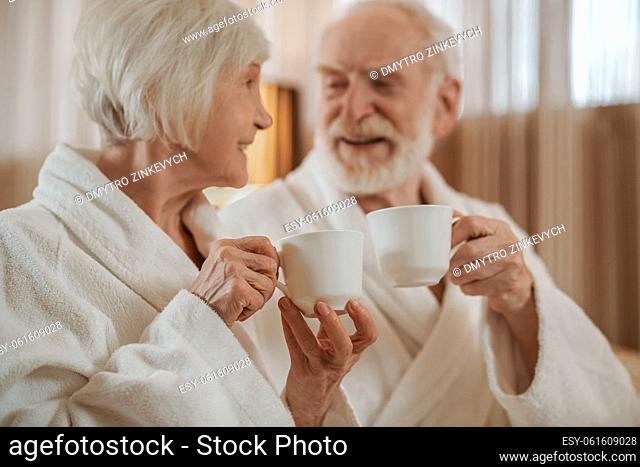 Morning coffee. A bearded man and a shor-haired woman having coffee together and smiling to each other