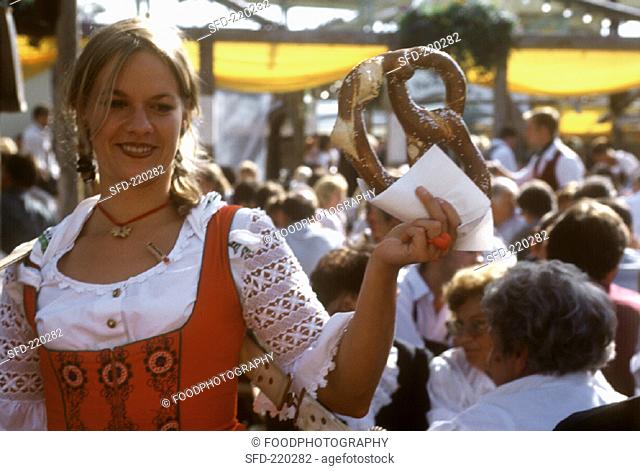 Young woman with giant pretzel in her hand at Oktoberfest (1)