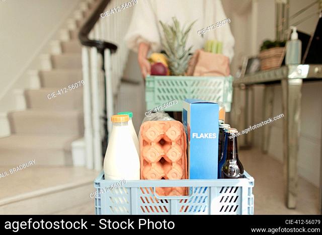 Woman receiving grocery delivery in foyer