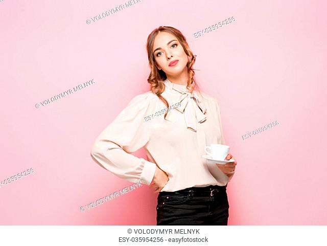 The serious frustrated young beautiful business woman with empty cup on pink studio background