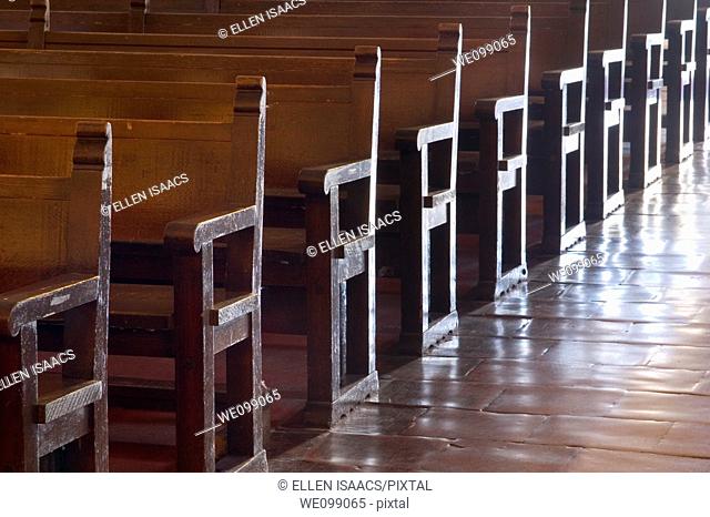 Rows of wood pews for worship in the Carmel Mission Basilica church Mission San Carlos Borromeo del Rio Carmelo in Carmel, California