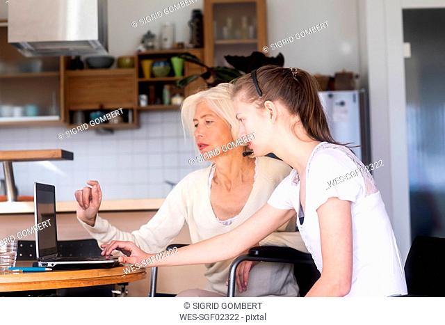 Daughter and mother in a wheelchair using a laptop