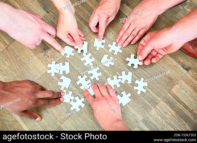 Hände von Leuten mit vielen Puzzleteilen als Konzept für Beschäftigungstherapie