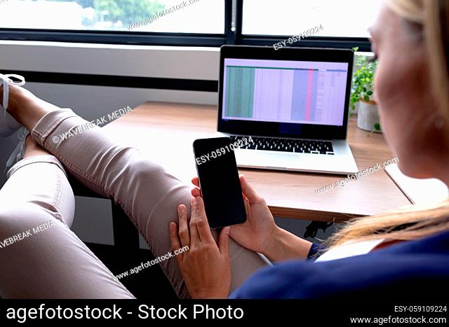 Caucasian businesswoman sitting at desk having video call conversation using smartphone
