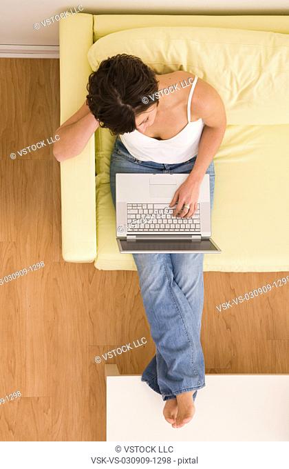USA, Illinois, Metamora, Young woman sitting on sofa with laptop