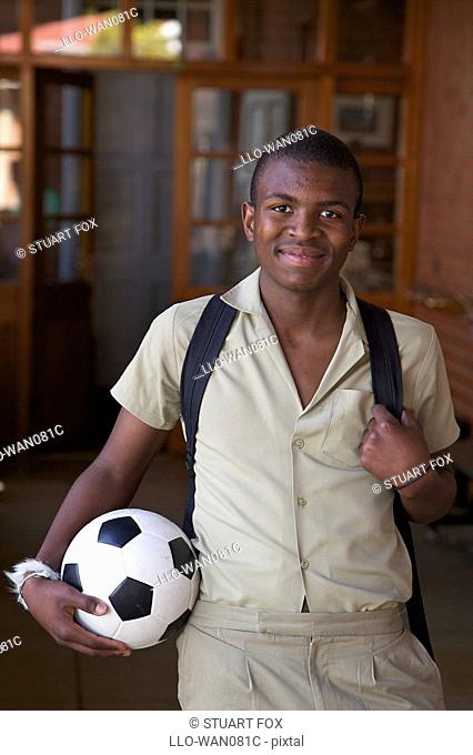 Portrait of a schoolboy standing with a soccer ball in the corridor, KwaZulu Natal Province, South Africa
