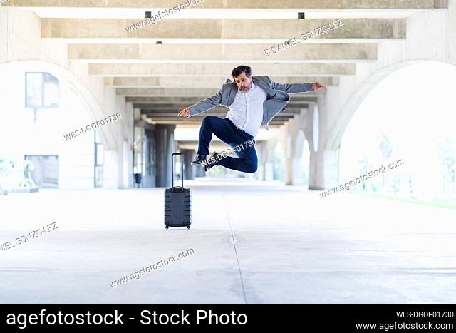 Carefree excited businessman jumping on concrete footpath