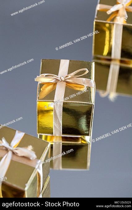 Group of gold sparkling gift boxes on grey background with reflection. A set of gold gift boxes for present, suprise, birthday, Christmas concept beauty