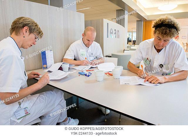 Tilburg, Netherlands. Three Physio therapists working on their planning for the treatment of hospital patients, while being on their coffee brake
