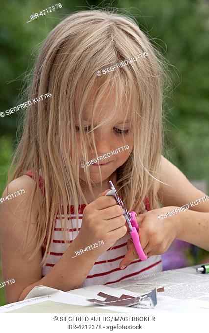 Little girl tinkering with scissors and paper