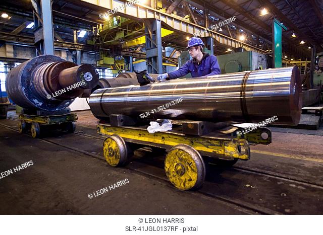 Worker cleaning metal in steel forge