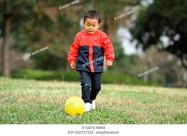 Japanese boy kicking a yellow ball (3 years old)