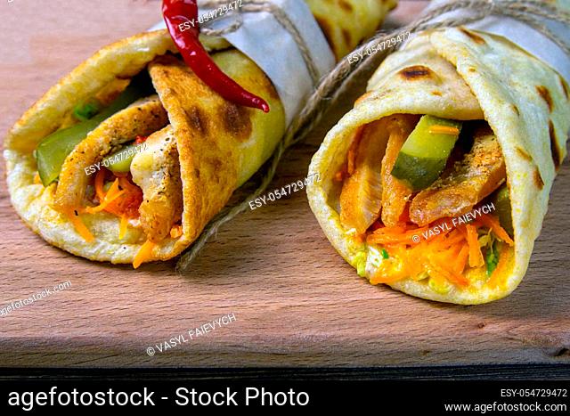 Two doner kebab with meat, vegetables and fries in pita bread close-up on a wooden table