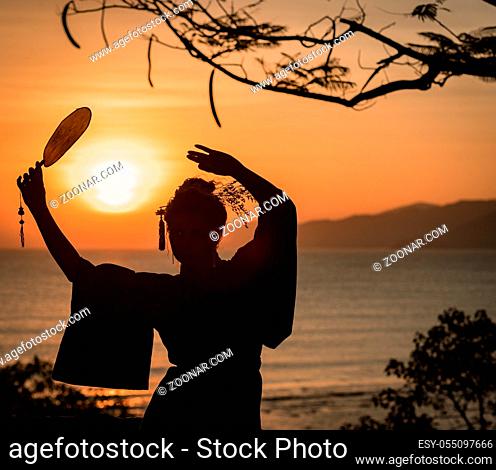 Silhouette of Japanese Geisha in kimono with fan at sunrise