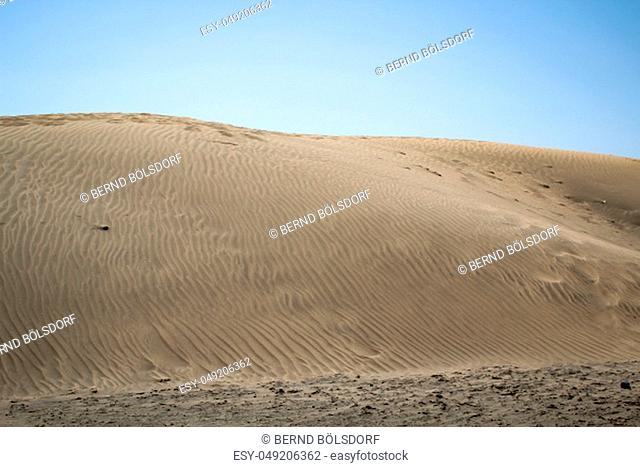 desert region with dunes under blue sky, sand textur