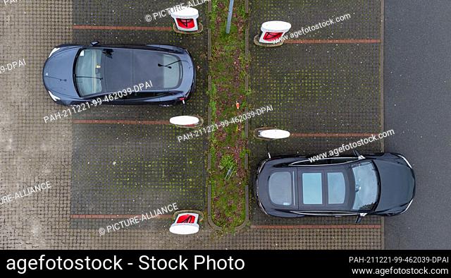 13 December 2021, Lower Saxony, Bispingen: Tesla electric vehicles being charged in a parking lot at fast charging stations (Supercharger) (shot with a drone)