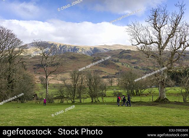 Walkers on the footpath from High Nest to Castlerigg Stone Circle in the Lake District National Park with the fells of Low Rigg