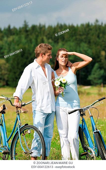 Romantic young couple walking with old bike