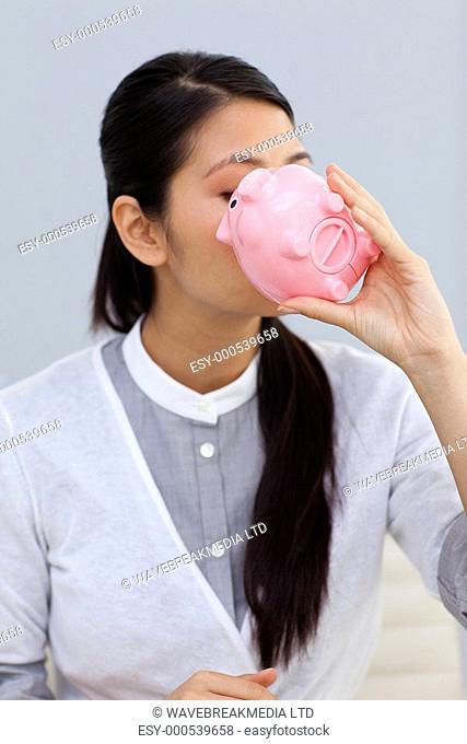 Businesswoman kissing a piggybank in the office